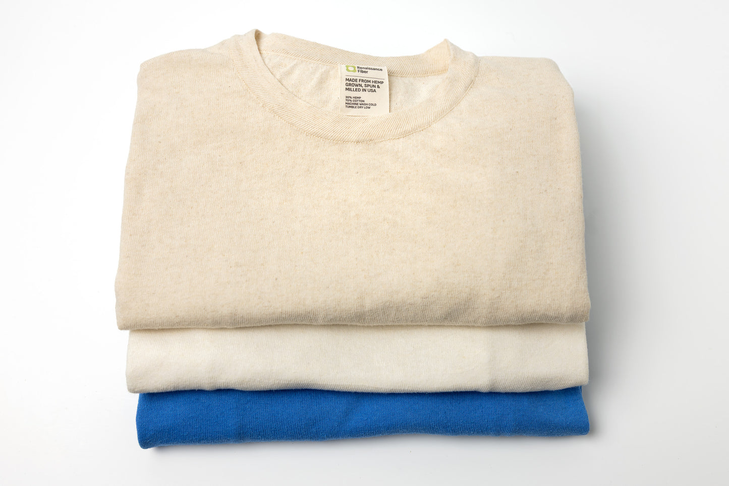 Folded beige and blue shirts on a white background